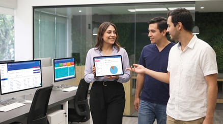Ingeniera biomédica conversando con dos profesionales en una oficina sobre la gestión de Ingeniería Biomédica con TINC CMMS.